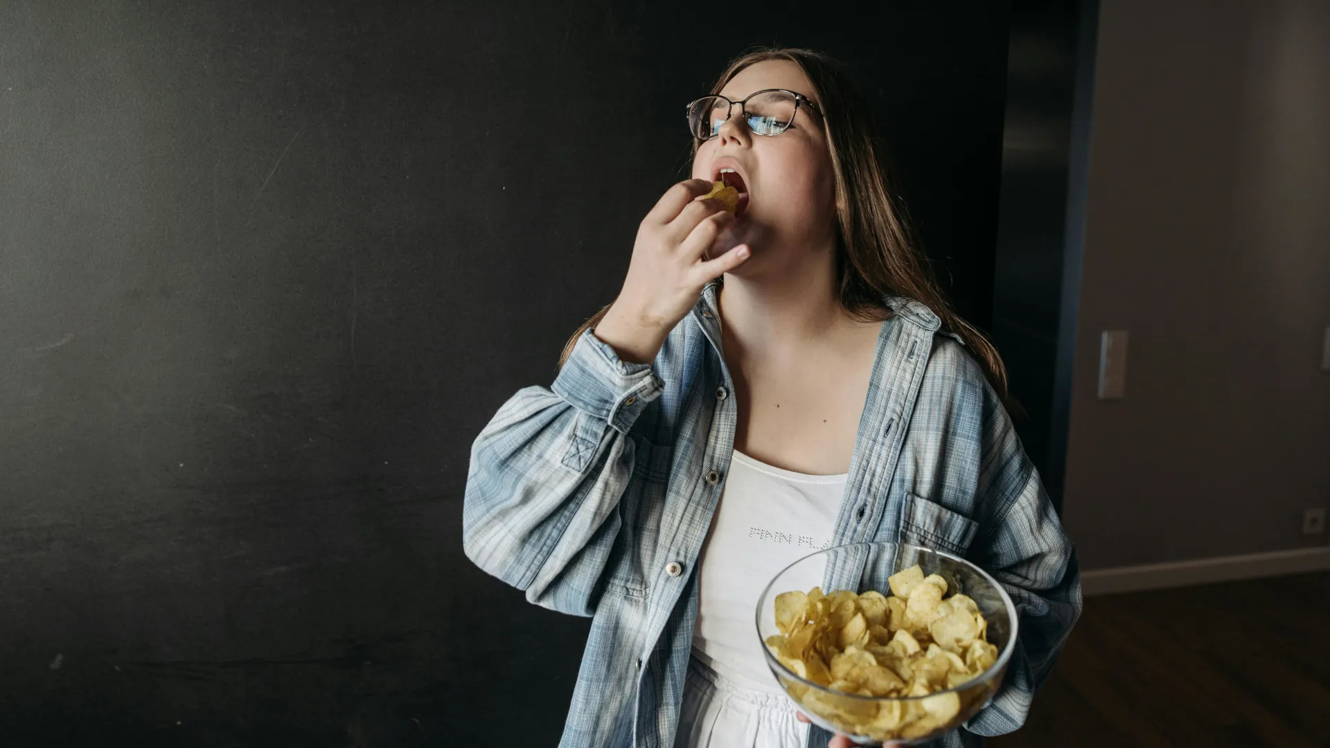 A young woman who is addicted to junk food. A bowl of crisps is slowly being eaten away.
