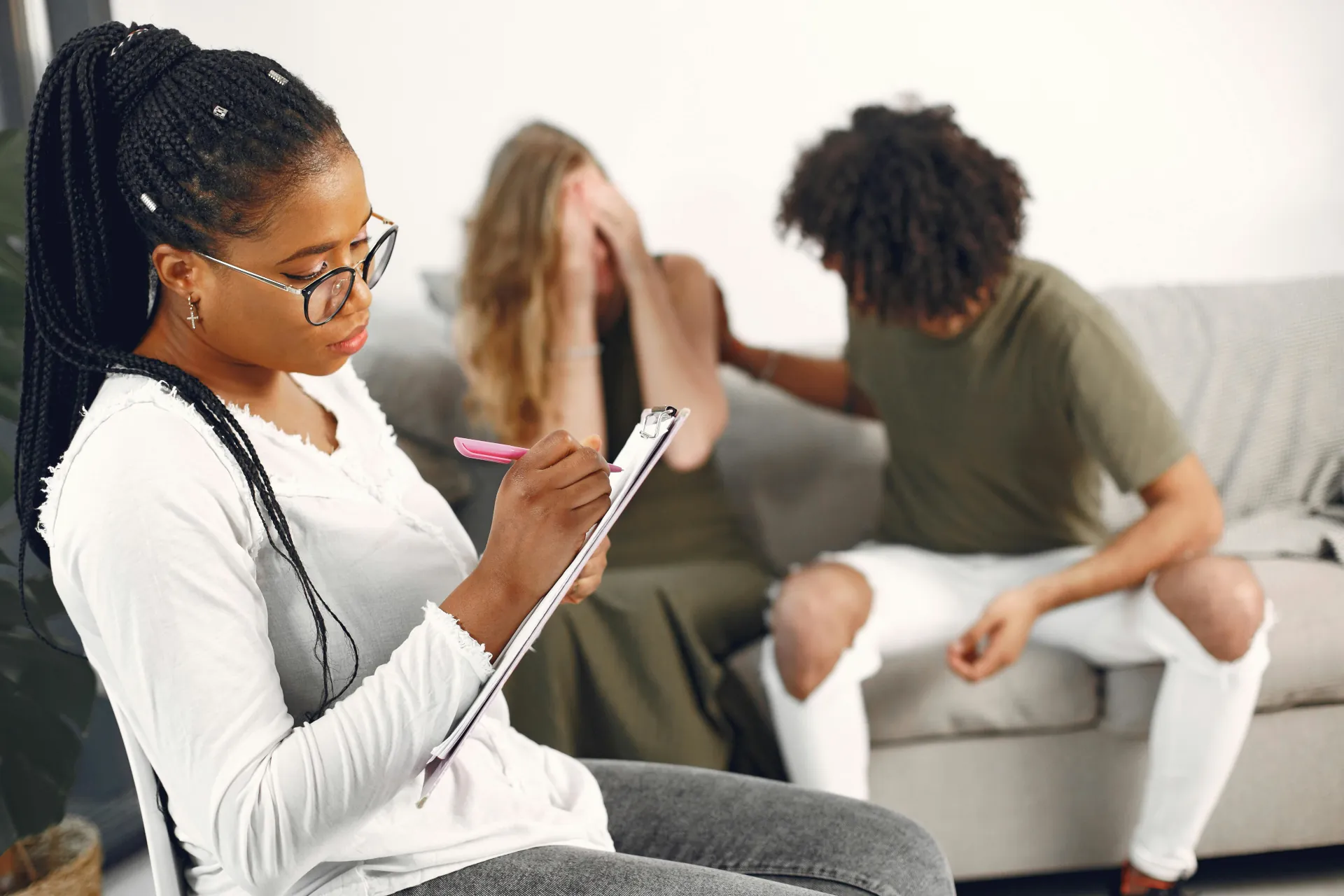 A therapist is taking notes during a Cognitive Behavioural Therapy between a couple who are trying to resolve their differences.